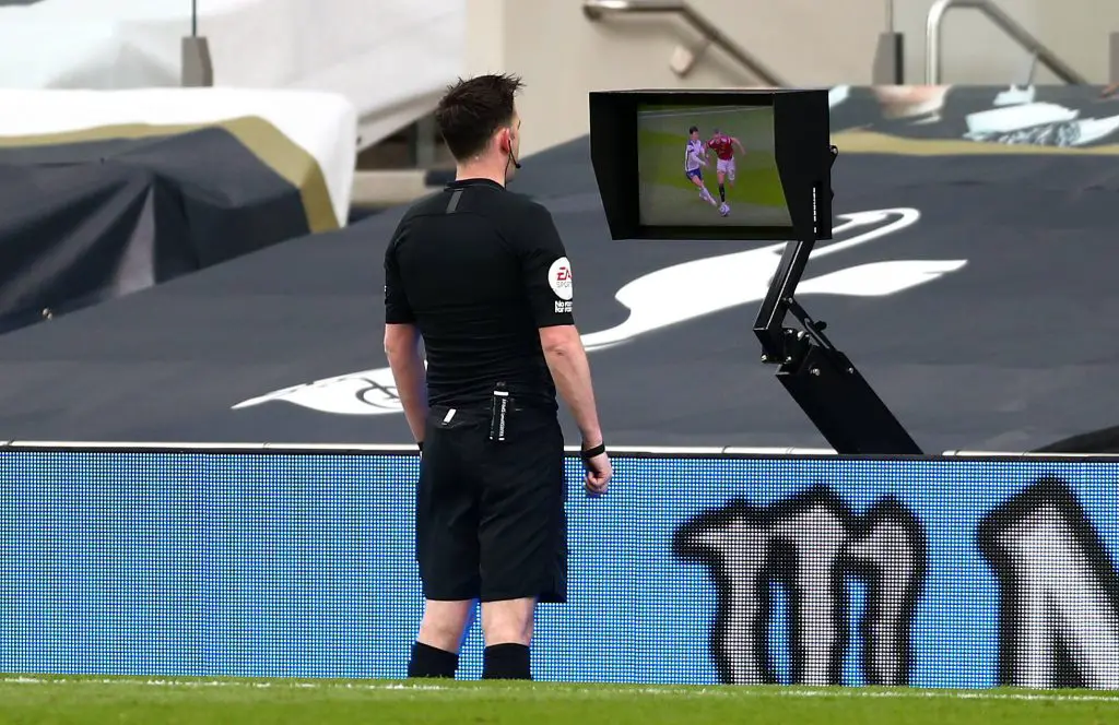 Referee Chris Kavanagh consults the pitch-side monitor to check Scott McTominay's foul on Son. (imago Images)