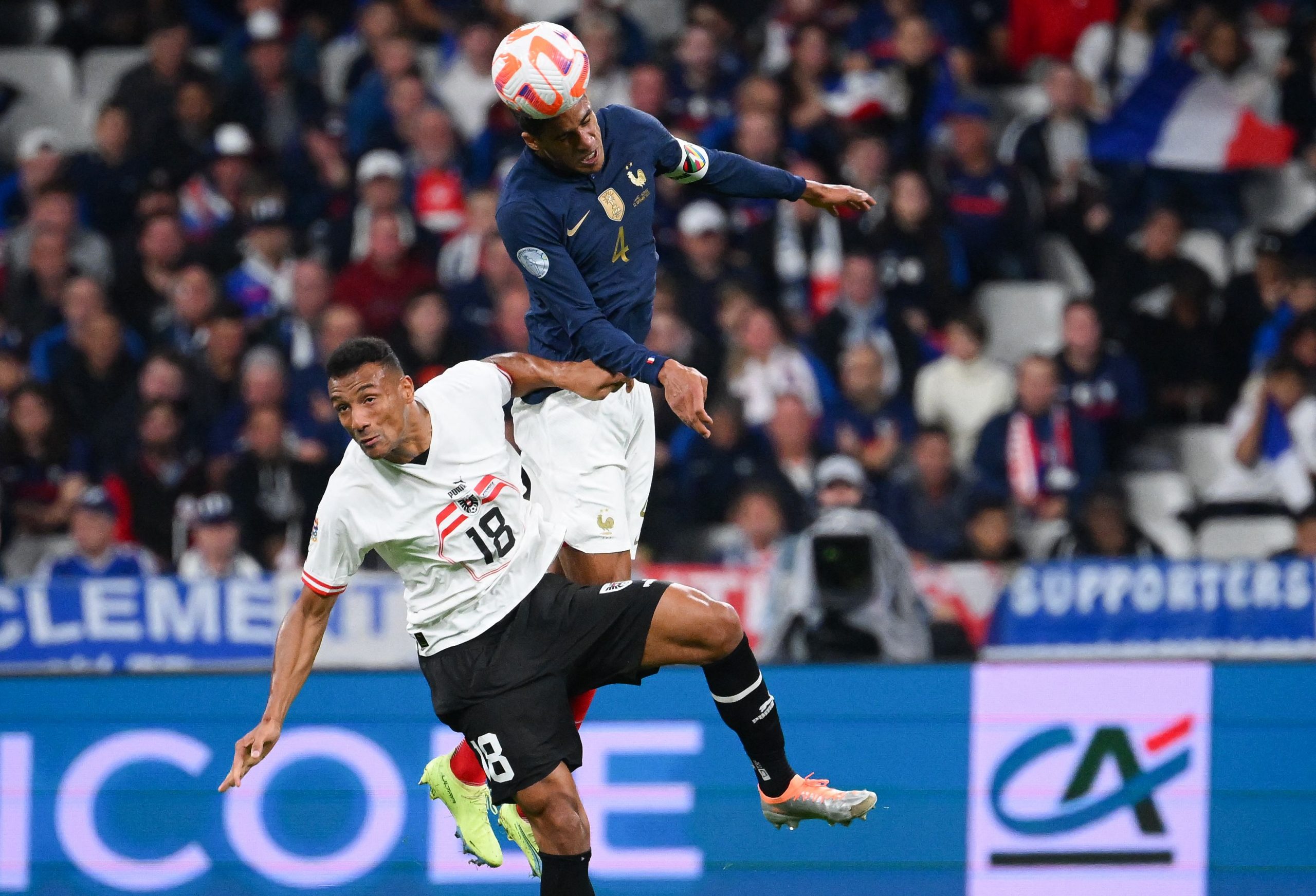 Raphael Varane (R) heads the ball from Austria's Karim Onisiw during a UEFA Nations League game.