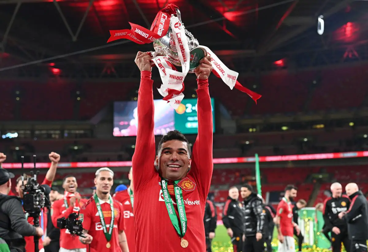 Manchester United's Brazilian midfielder Casemiro holds the trophy as Manchester United players celebrate their win on the pitch after the English League Cup final football match between Manchester United and Newcastle United at Wembley Stadium, north-west London on February 26, 2023. - Manchester United clinched their first major trophy for six years with a ruthless 2-0 win against Newcastle in the League Cup final at Wembley on Sunday