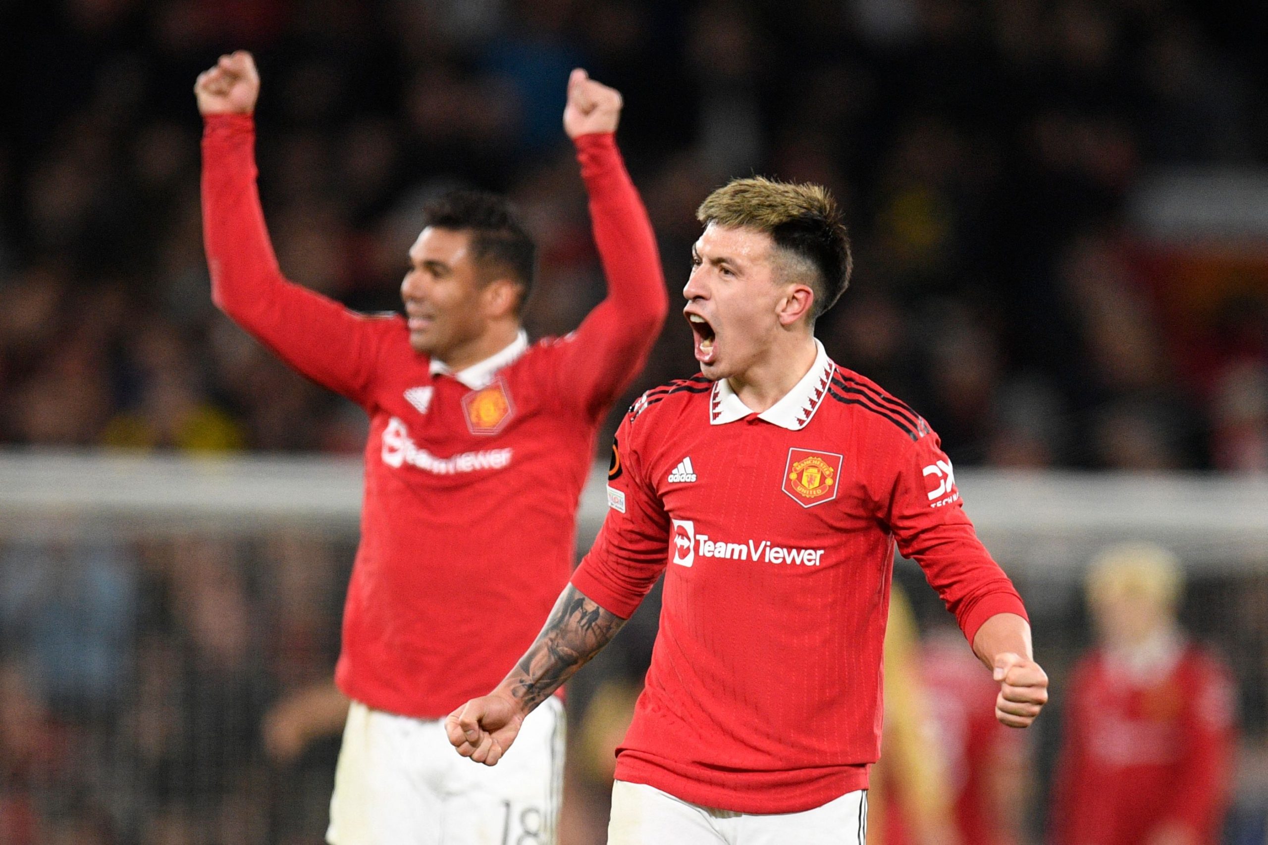 Manchester United's Argentinian defender Lisandro Martinez (R) and Manchester United's Brazilian midfielder Casemiro celebrate at the end of the UEFA Europa league knockout round play-off second leg football match between Manchester United and FC Barcelona at Old Trafford stadium in Manchester, north west England, on February 23, 2023. - Manchester United won 2 - 1 against FC Barcelona