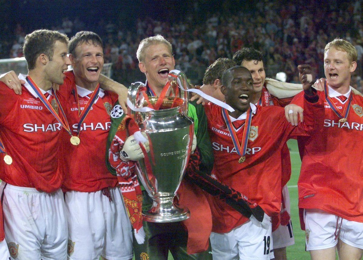 Manchester United's treble winners in the 1998-99 season as Peter Schmeichel holds the UEFA Champions League trophy. (Photo by ERIC CABANIS/AFP via Getty Images)
